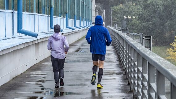 Два человека на пробежке во время дождя 